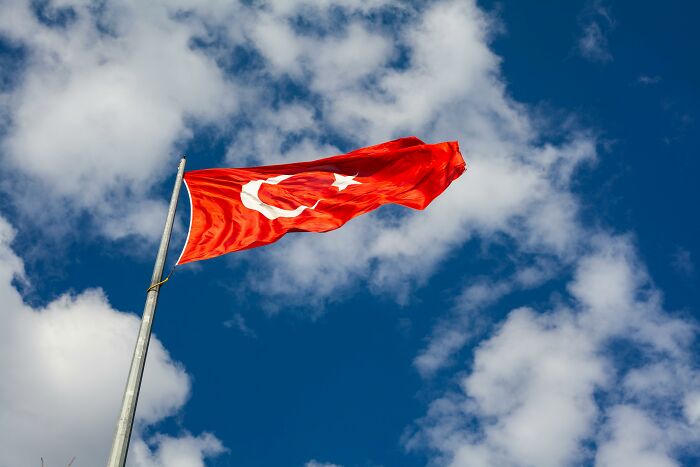 Turkish flag waving against a cloudy sky, representing overlooked historical events.