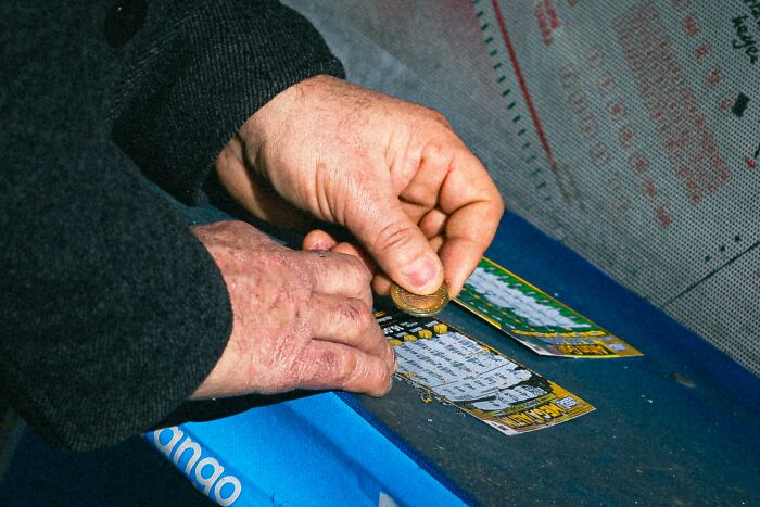 "Hands using a coin to scrape a lottery ticket, surrounded by theories of luck and chance."