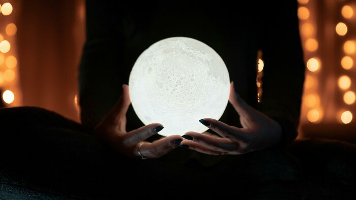 Person holding a glowing moon lamp, illustrating overlooked historical events.