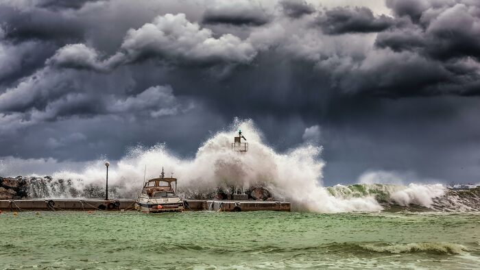 Rough seas and storm waves crashing over a pier, symbolizing overlooked historical events in maritime history.