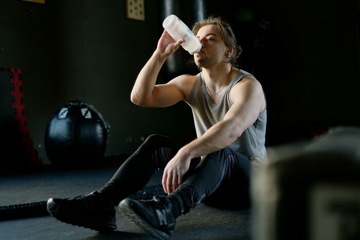Man drinking water at gym, illustrating how buying things improved his lifestyle.