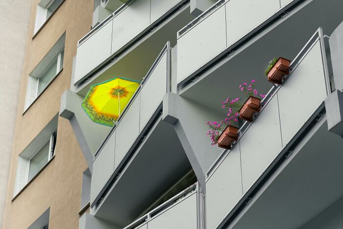 A modern apartment building with balconies, featuring a yellow umbrella and flower pots, highlighting financial stereotypes.