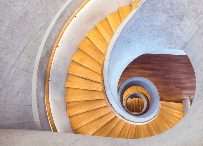 Spiral wooden staircase with a concrete railing, highlighting a potentially dangerous everyday element.