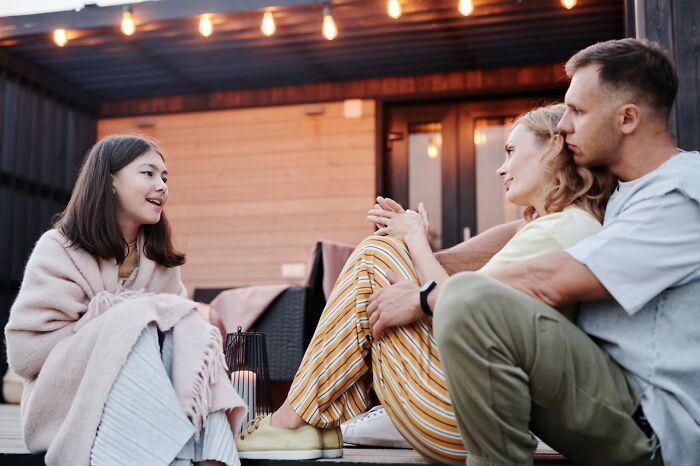 Parents and teen talking on a porch, depicting relational tension and infuriating actions affecting their connection.
