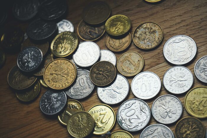 Coins scattered on a wooden table, representing ways to slash household budgets.