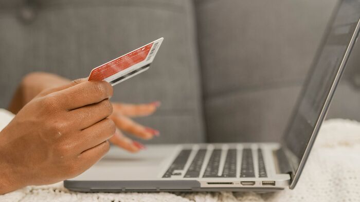 "Person holding a credit card while using a laptop, symbolizing overlooked historical events in online shopping."