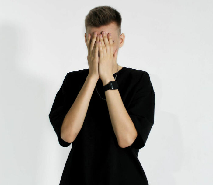 Teen covering face with hands in frustration, symbolizing parent-teen conflict.