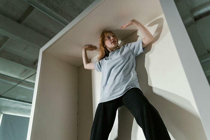 Woman inside a large box, pressing against the top, representing a potentially dangerous everyday scenario.