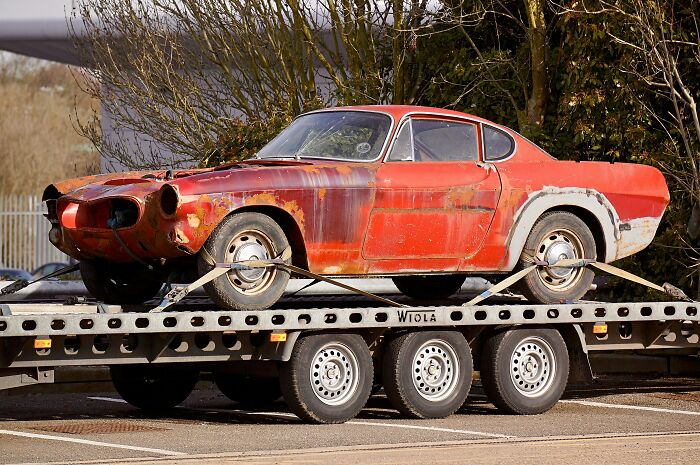 Rusty red car on a trailer, illustrating how everyday things might seem harmless but could be dangerous.