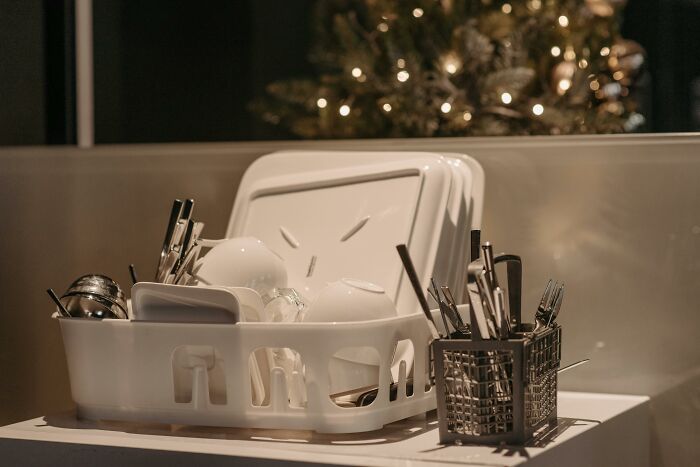Affordable kitchen setup with a dish rack, utensils, and crockery near a decorated tree, highlighting simplicity in everyday life.