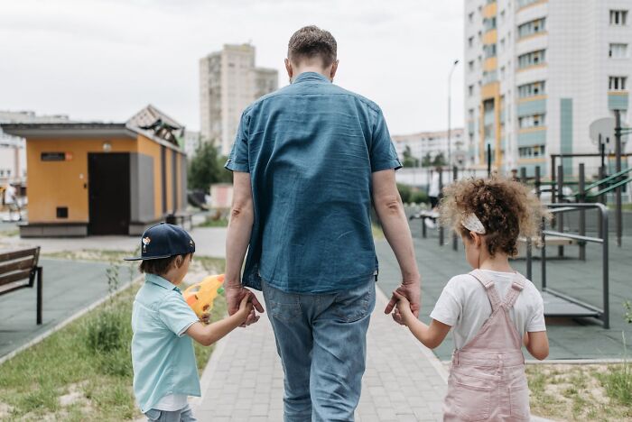 Man walking with two children in a park, promoting understanding and acceptance.