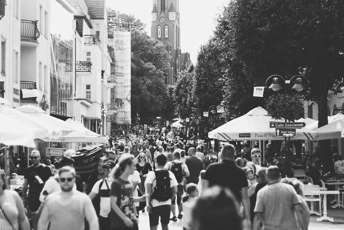 Crowded street scene with people walking, umbrellas, and buildings, illustrating overlooked historical events.