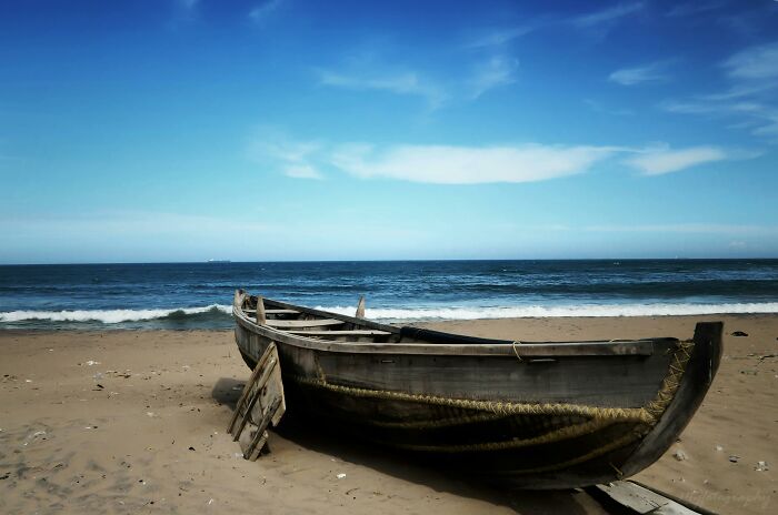 Abandoned boat on a deserted beach, possibly linked to weird unsolved mysteries.