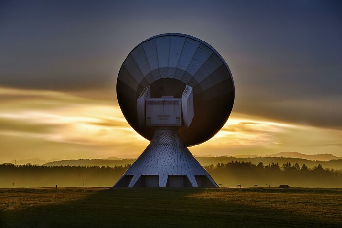 Giant satellite dish against sunset, symbolizing weird unsolved mysteries.