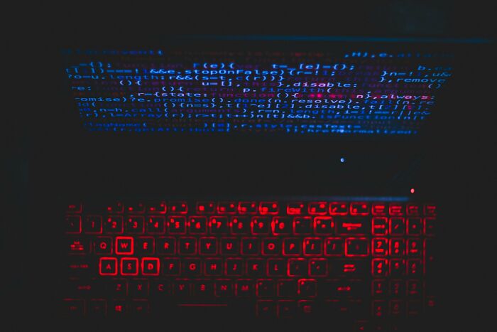 Computer screen with code and illuminated red keyboard, evoking themes of controversial conspiracy theories.