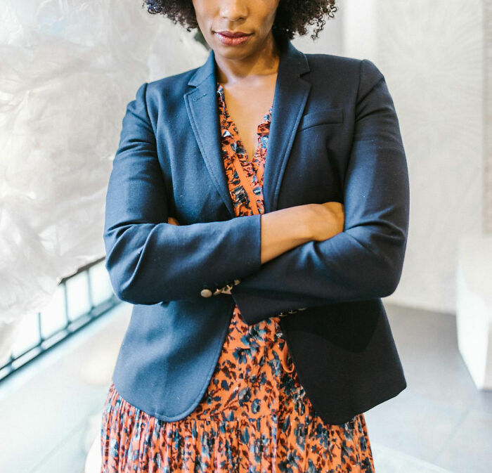 A woman in a blue blazer looks serious, showcasing a parent's infuriating actions affecting their teen relationship.