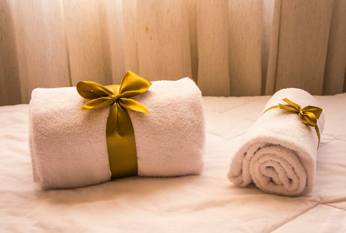 Two rolled white towels with golden ribbons.