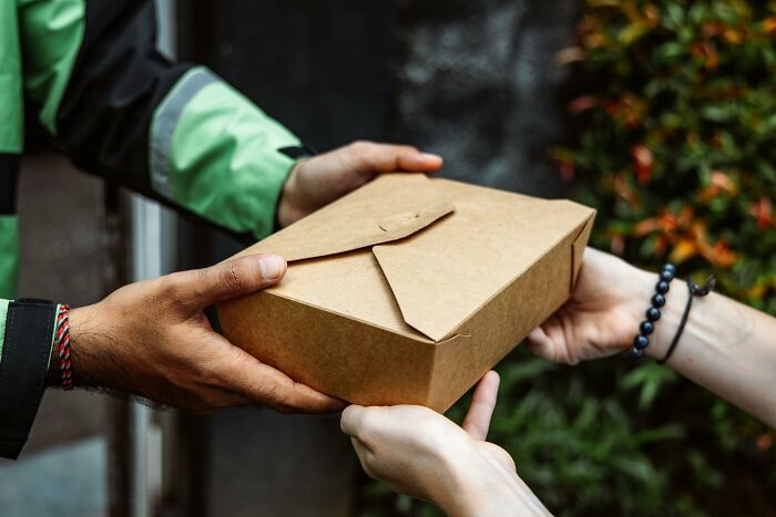 Hands exchanging a delivery package outdoors, highlighting delivery stories.