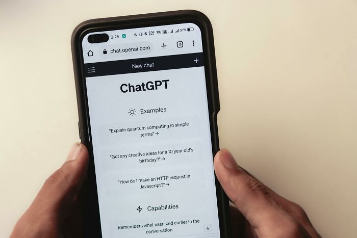 Person holding smartphone with ChatGPT app open, displaying modern technology examples.