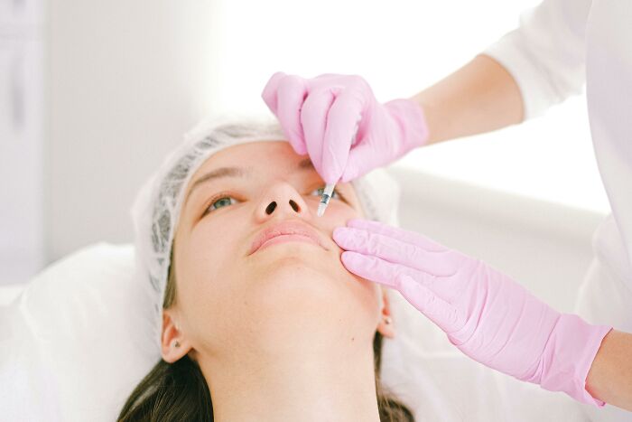 Person receiving a cosmetic procedure in a clinic setting, showcasing a trend people may avoid for looking uncool.