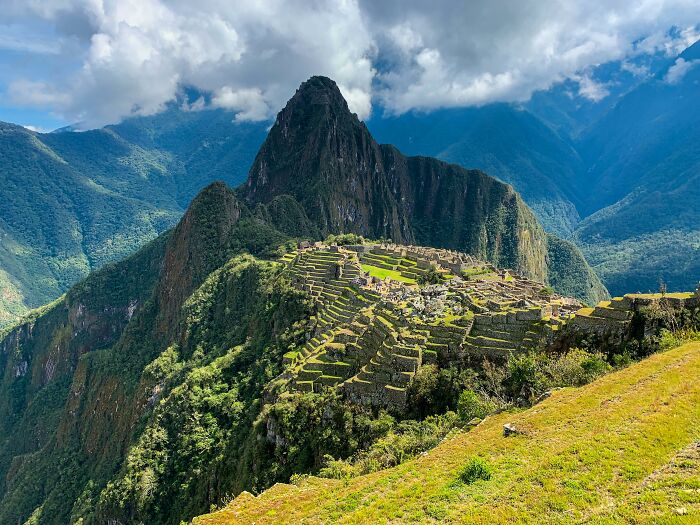 Machu Picchu under cloudy skies, lush green terraces, mountains, worst country ever visited keyword focus.
