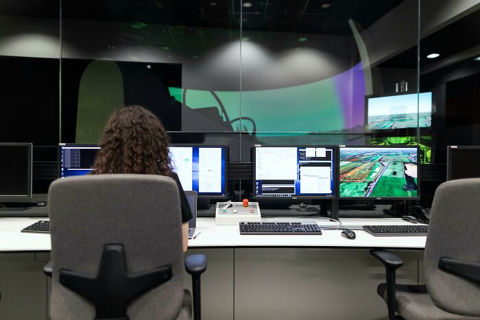 Person at a control center with multiple screens, associated with controversial conspiracy theories.