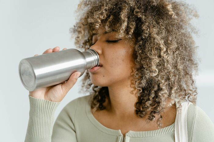 Person drinking from a stainless steel bottle, highlighting affordable ways to make life easier.