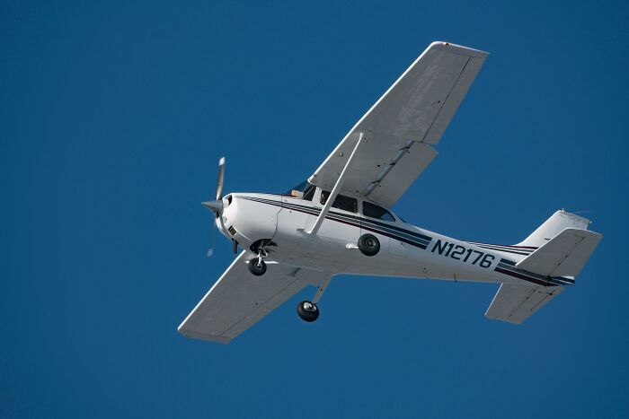 A small airplane flies against a clear blue sky, relating to overlooked historical events in aviation.