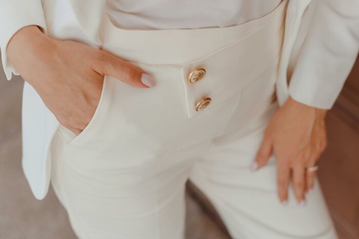Person in a white suit, with hand in pocket, showcasing fashion elegance, linked to controversial conspiracy theories.