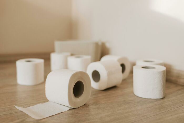 Household budget tip: several toilet paper rolls on a wooden floor, highlighting cost-saving strategies.