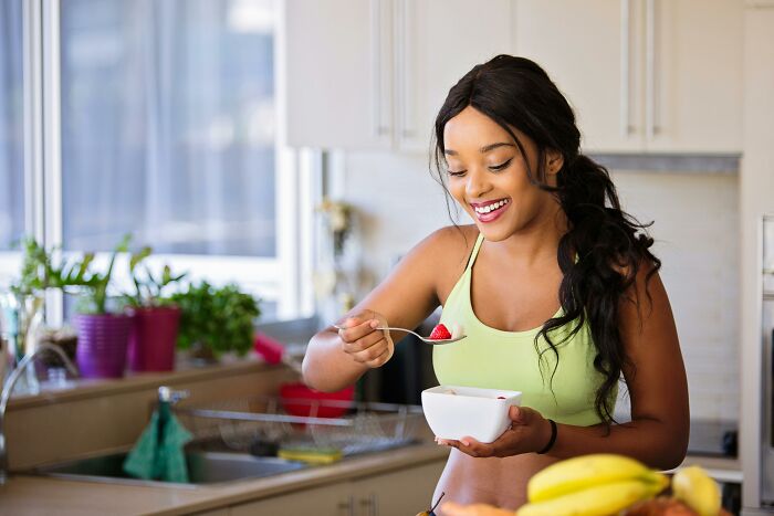 Woman in kitchen enjoying a bowl of fruit.