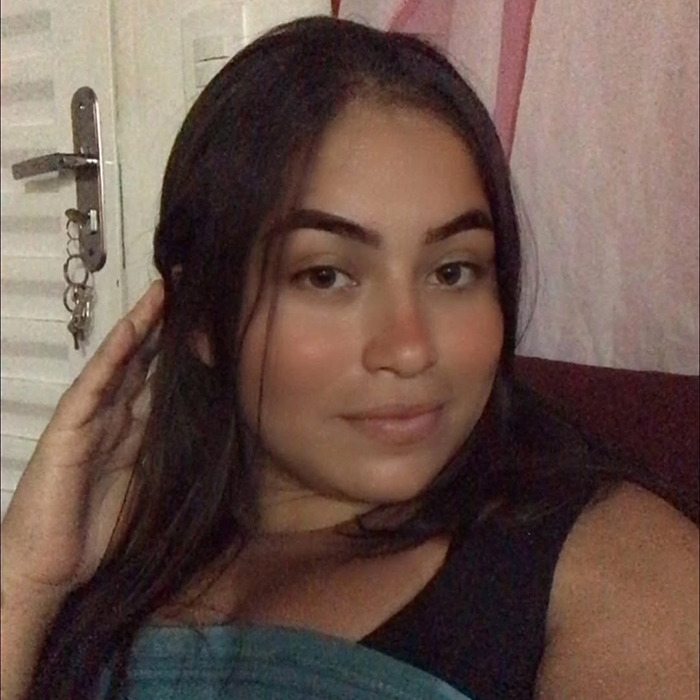 Joyce Sousa Ara&uacute;jo at home, smiling and holding her hair, related to life support debate.