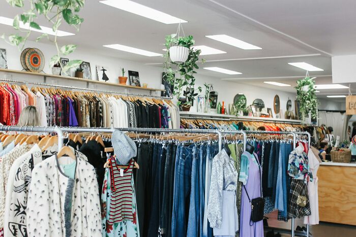 Store with racks of colorful clothing and plants.