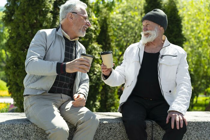 Two older men enjoying coffee outside, engaging in conversation, illustrating psychological tricks in social settings.