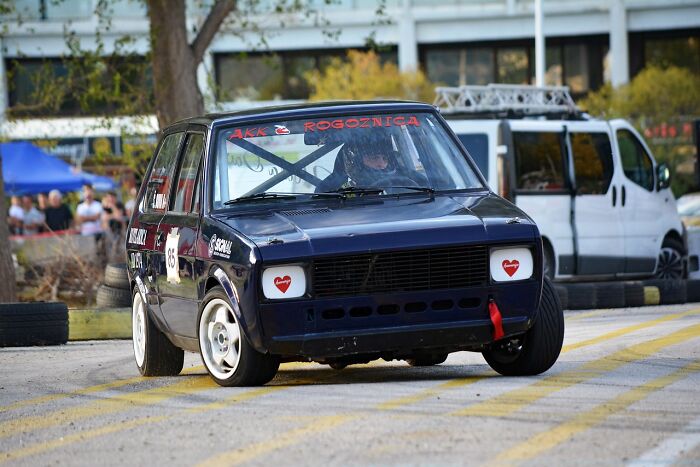 A compact car racing on a track, showcasing a budget-friendly motorsport activity.