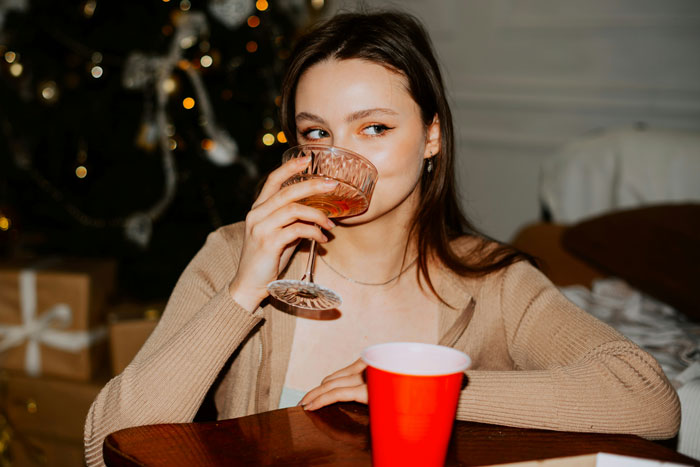 Woman drinking at a party, seated at a table. Woman drinking at a party, seated at a table.