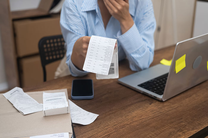 Person at a desk reviewing receipts, with a laptop and smartphone, highlighting reimbursement issues. Person at a desk reviewing receipts, with a laptop and smartphone, highlighting reimbursement issues.