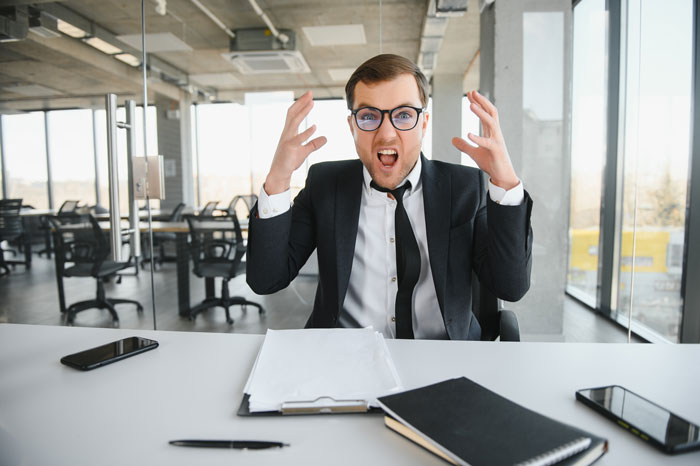 Man in a suit in an office, appearing frustrated, with papers on the desk, related to reimbursement and receipts issue. Man in a suit in an office, appearing frustrated, with papers on the desk, related to reimbursement and receipts issue.