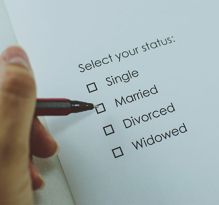 A hand holding a pen, marking a box on a relationship status form during a job interview.