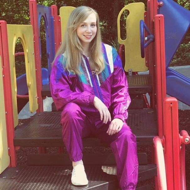 Person in retro purple tracksuit sitting on a colorful playground, evoking nostalgia for the good old days.