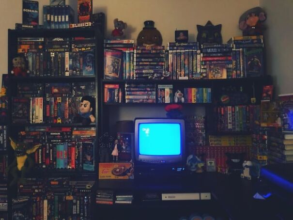 Retro finds in a cozy room with shelves full of VHS tapes and a vintage TV set displaying a blue screen.