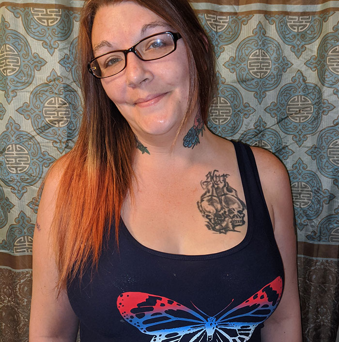 Woman with glasses and tattoos wearing a black tank top with a butterfly design. Woman with glasses and tattoos wearing a black tank top with a butterfly design.