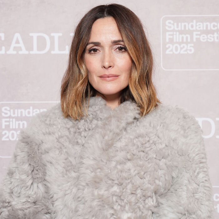 Rose Byrne at Sundance Film Festival, wearing a gray fur coat against a branded backdrop.