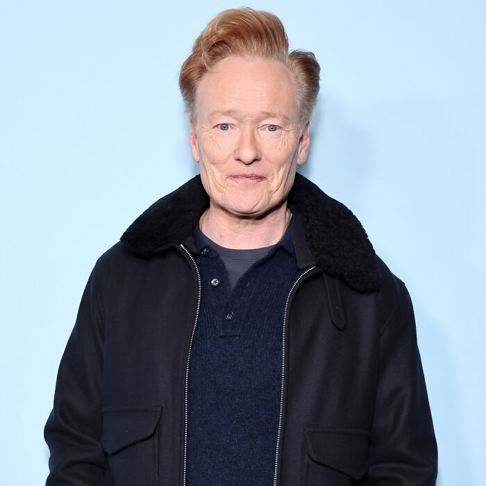 Conan O&rsquo;Brien in a black jacket against a blue background, related to Sundance film event, smiling.