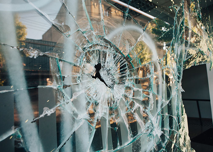 "Shattered glass window in one of the scariest cities, reflecting urban decay and danger."