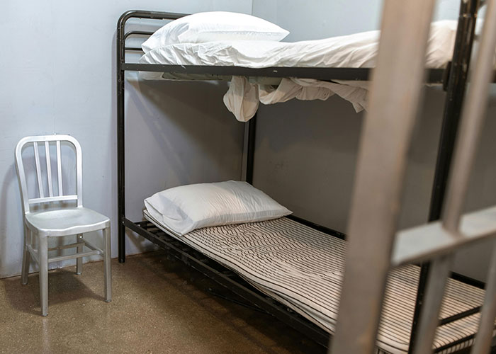 A sparse prison cell with bunk beds and a metal chair, representing one of the scariest cities.