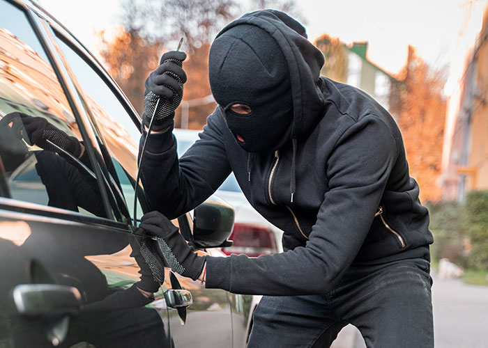 Masked person attempting to break into a car in one of the scariest cities.