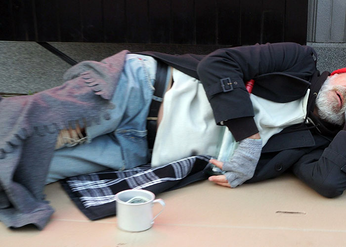 A person experiencing homelessness sleeping on the street in one of the scariest cities.
