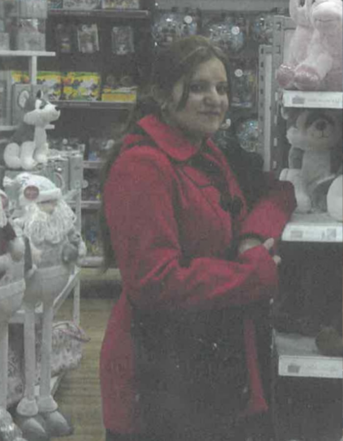 Woman in a red coat stands in a toy store, arranged marriage bride theme.
