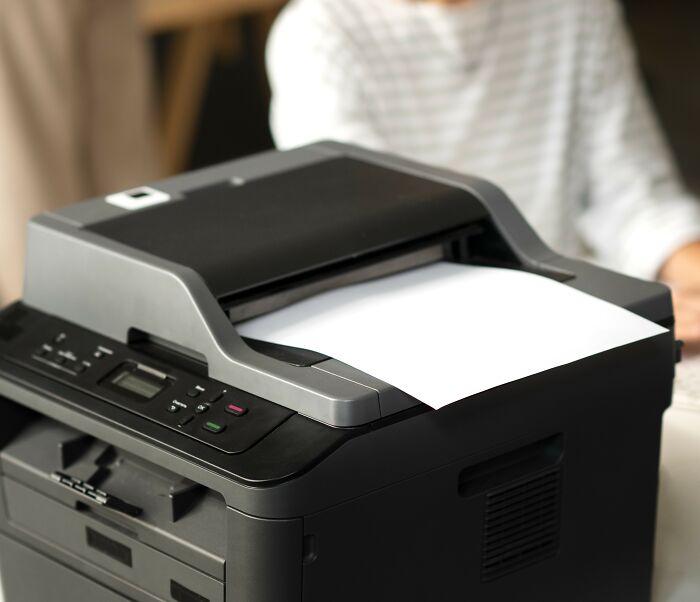 Affordable black printer on a desk with paper, used to make life easier at home or office.